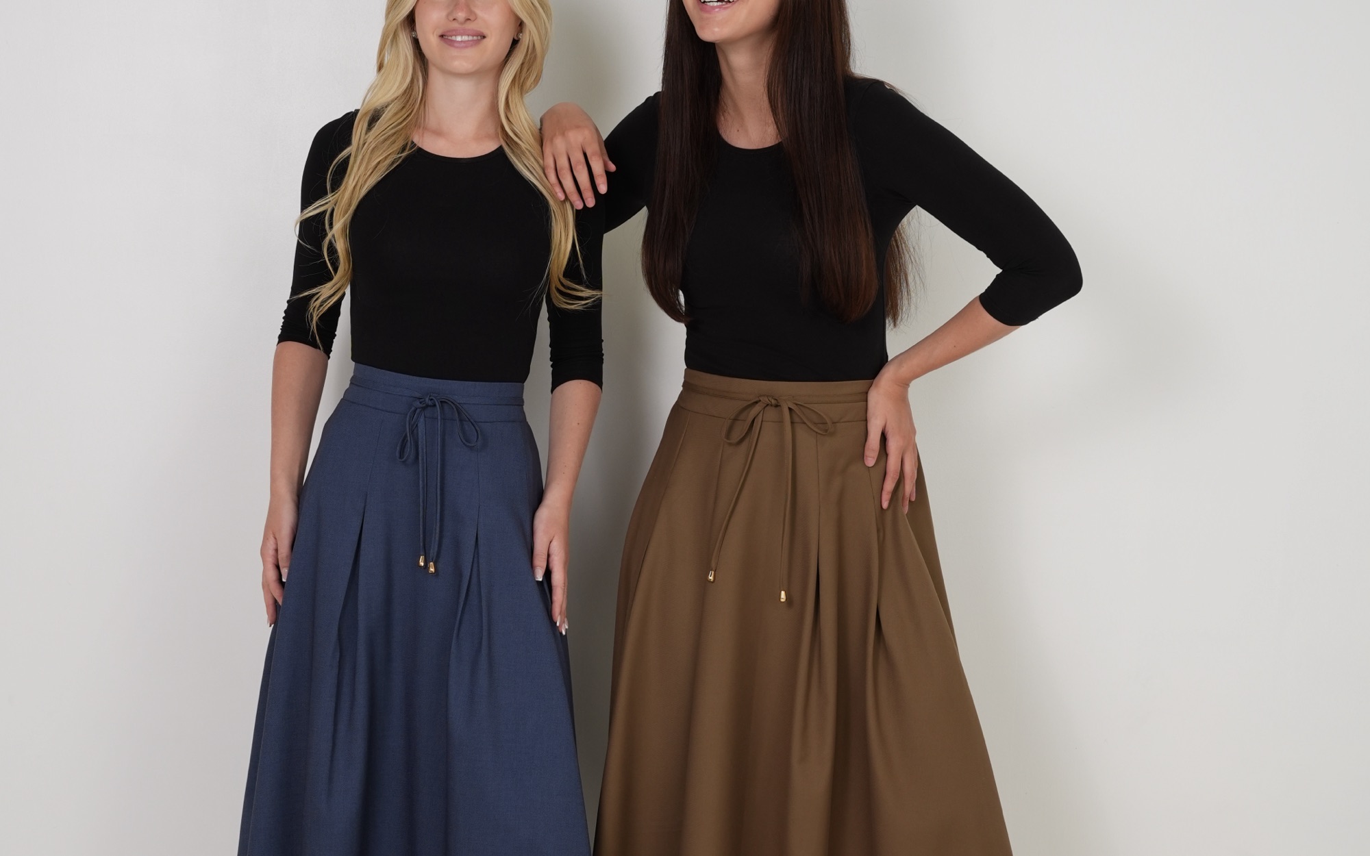 Two models wearing PEODE skirts in river blue and camel
