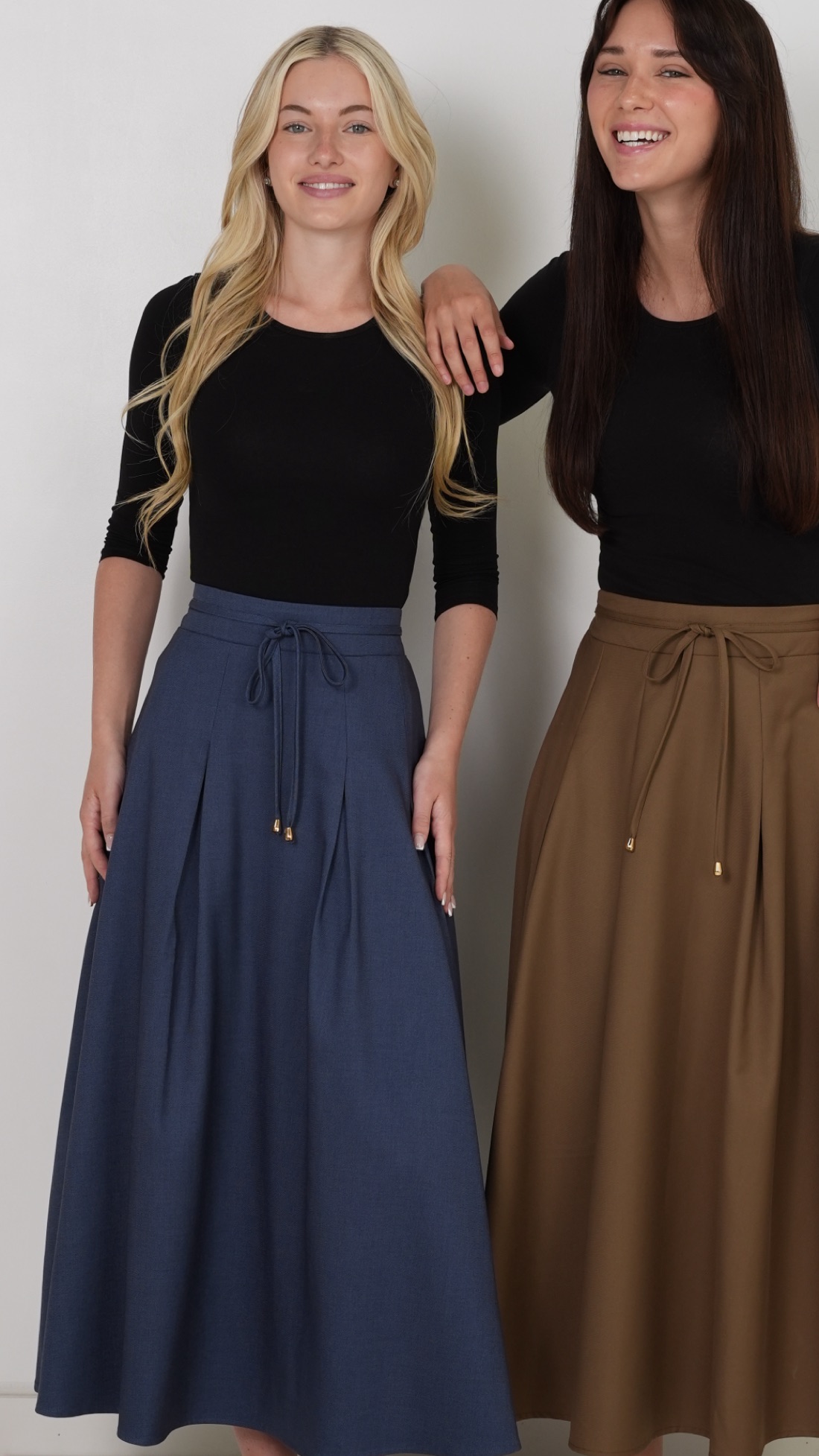 Two models wearing river-blue and camel maxi skirts