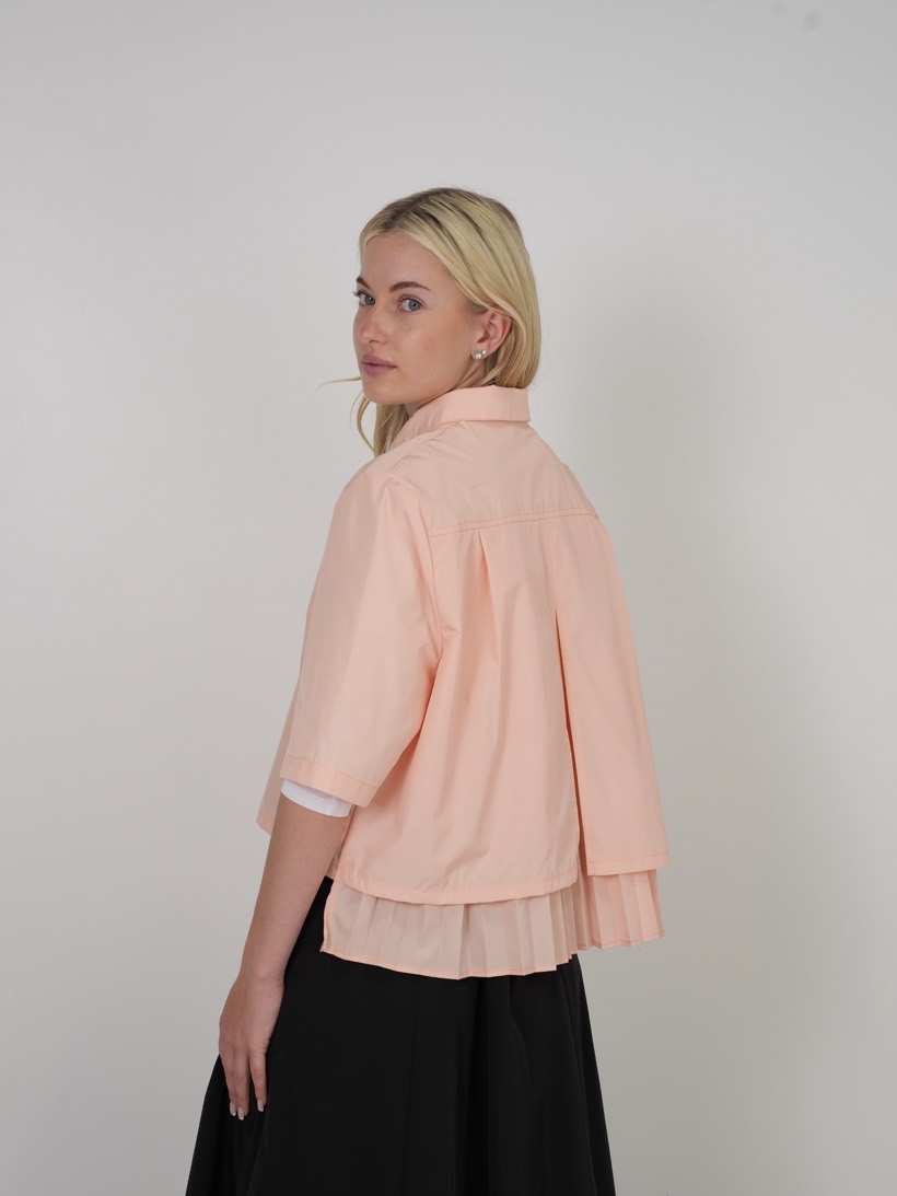 Peach blouse worn over black, side view